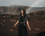 concept-photo-of-smiling-woman-in-a-desert-with-a-rainbow-behind-her